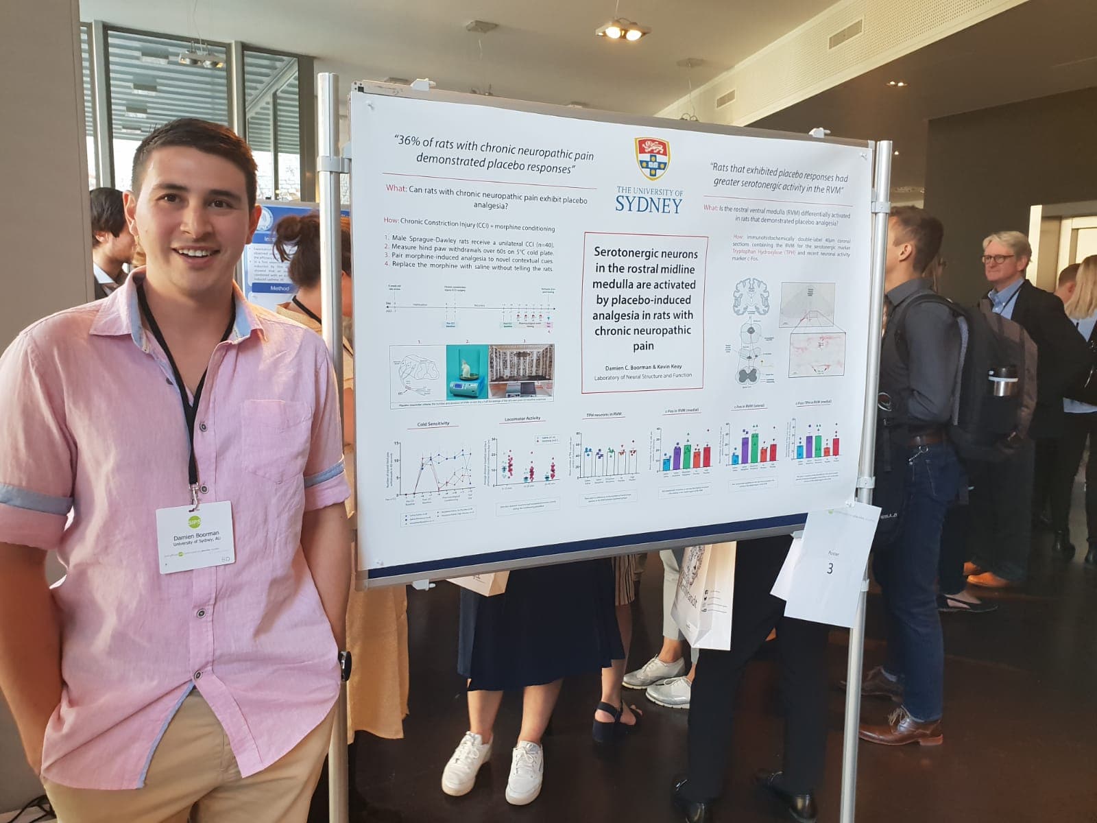 Damien Boorman standing beside a scientific poster about placebo analgesia